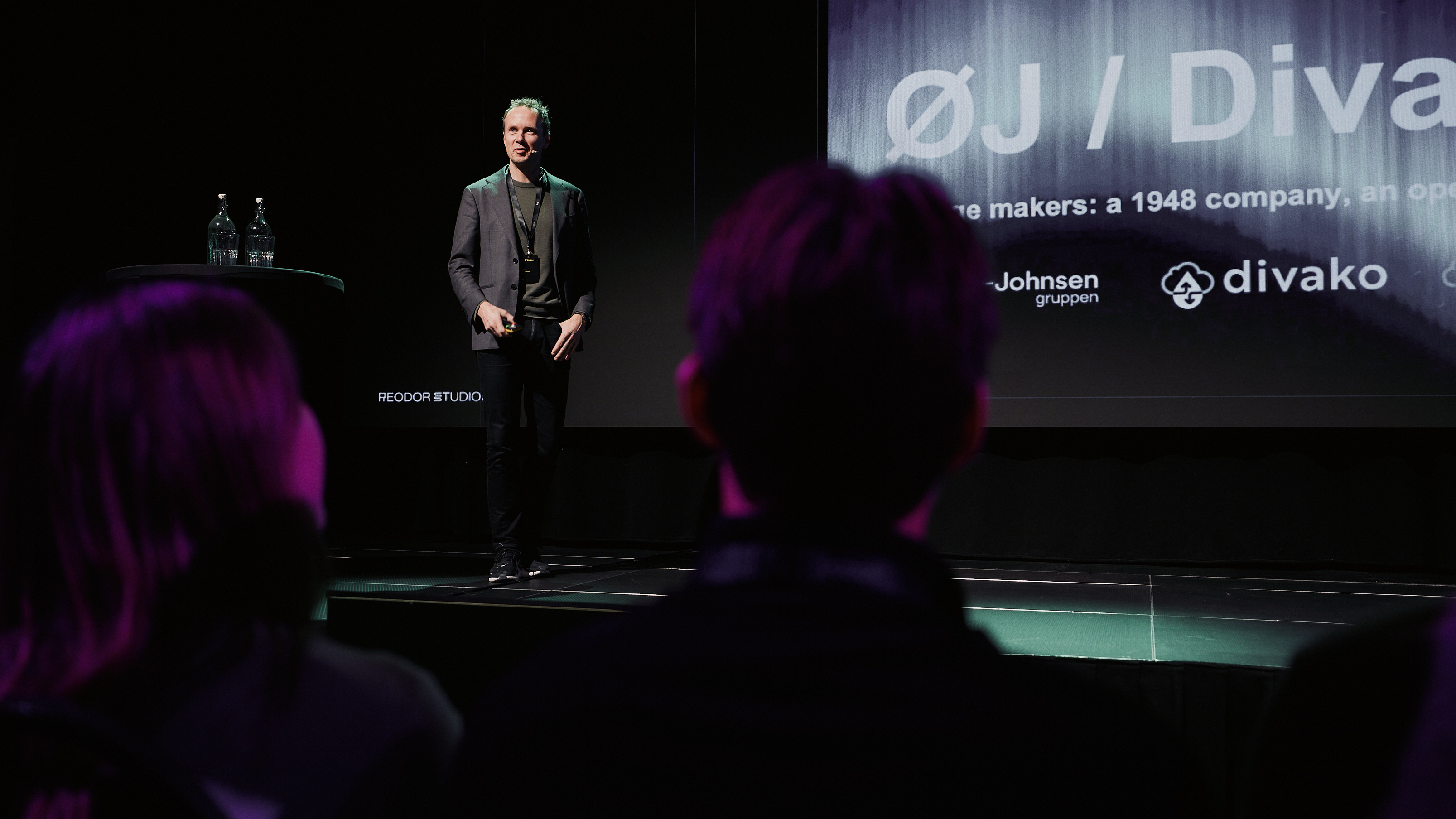 Anders Øwre-Johnsen on stage with the Øwre-Johnsen and Divako presentation behind him